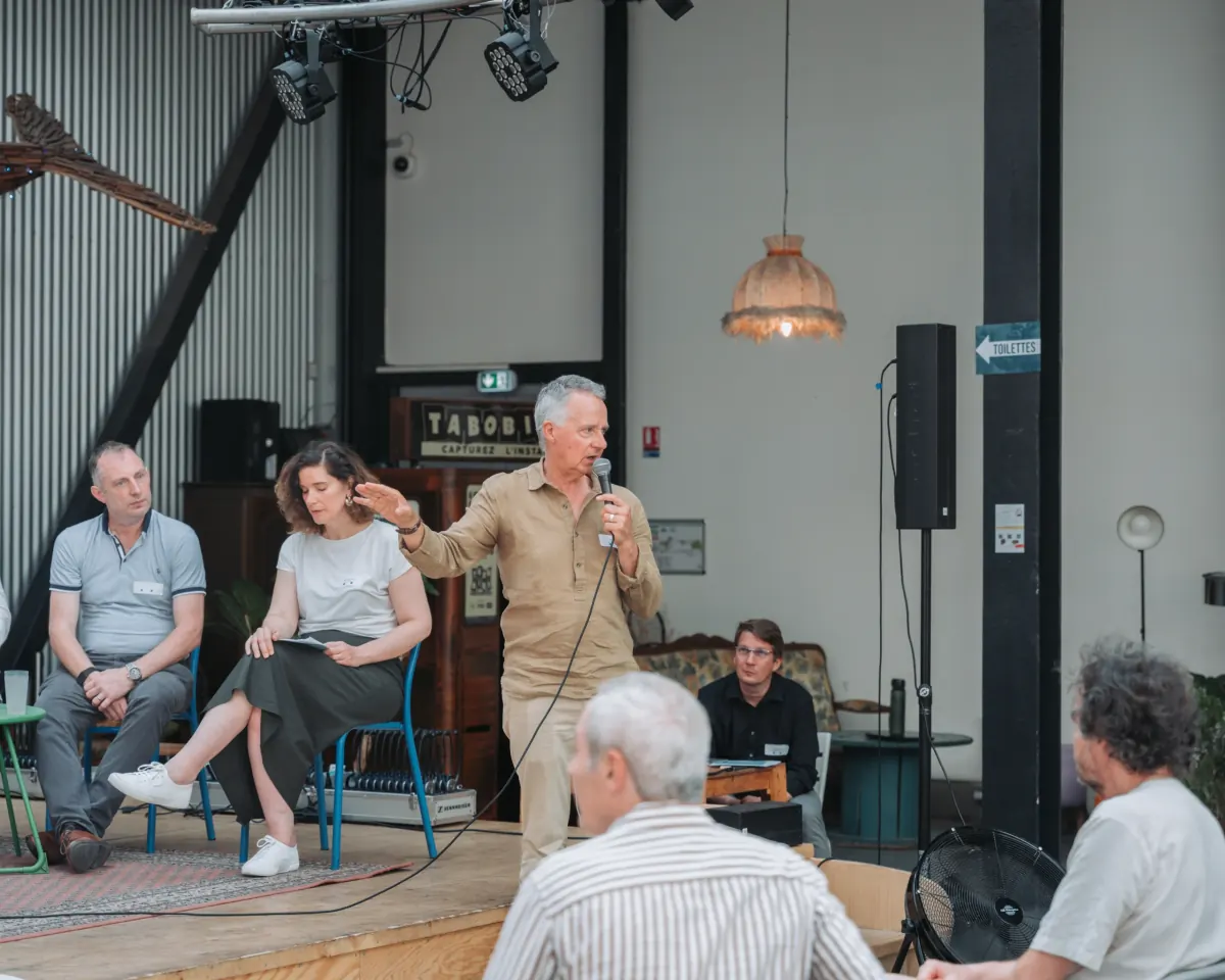 Intervenant au micro pendant une table ronde, personne désignée au brief comme prioritaire pour le photographe