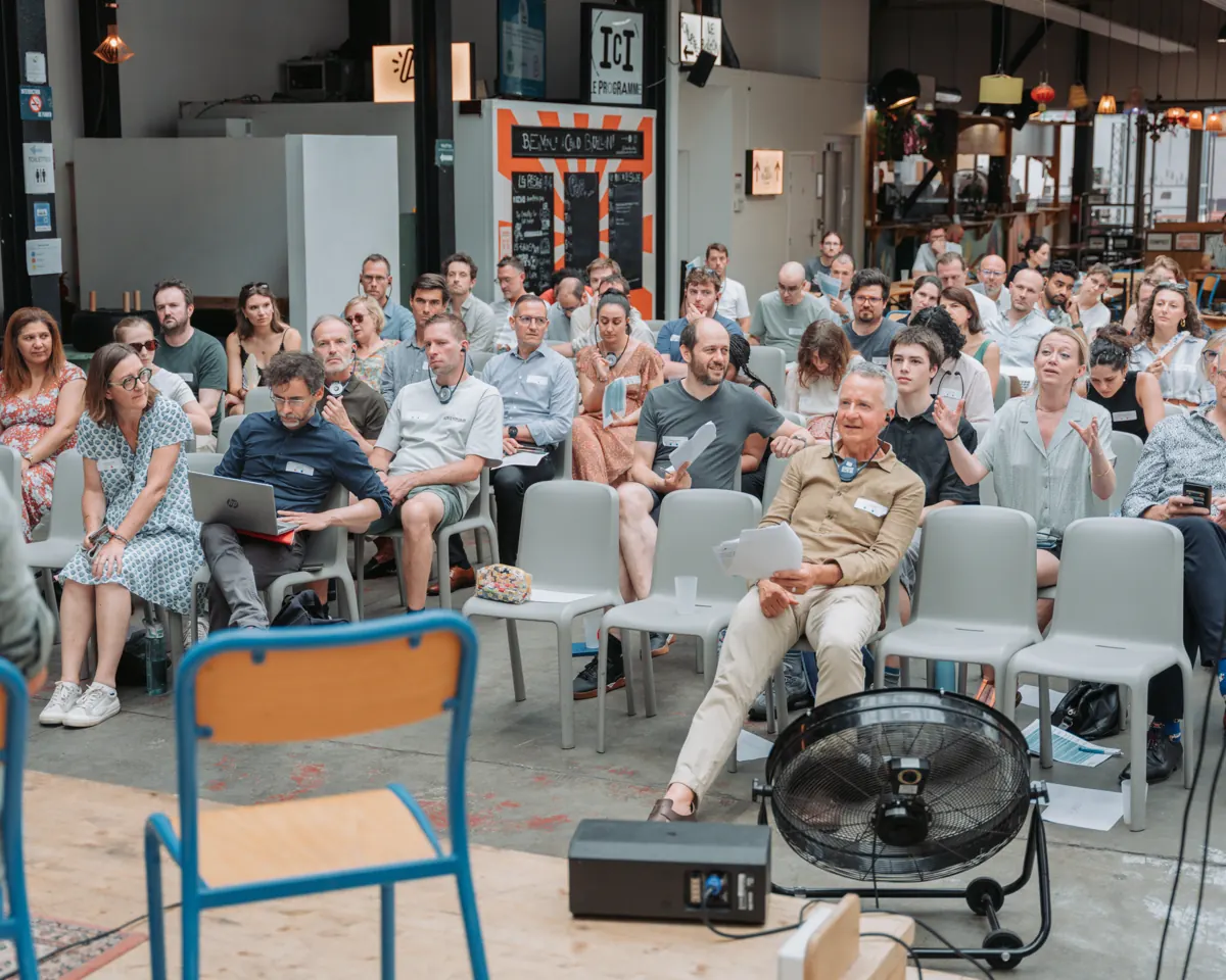 Public attentif pendant une conférence d'entreprise, photographié de face depuis le côté de la scène
