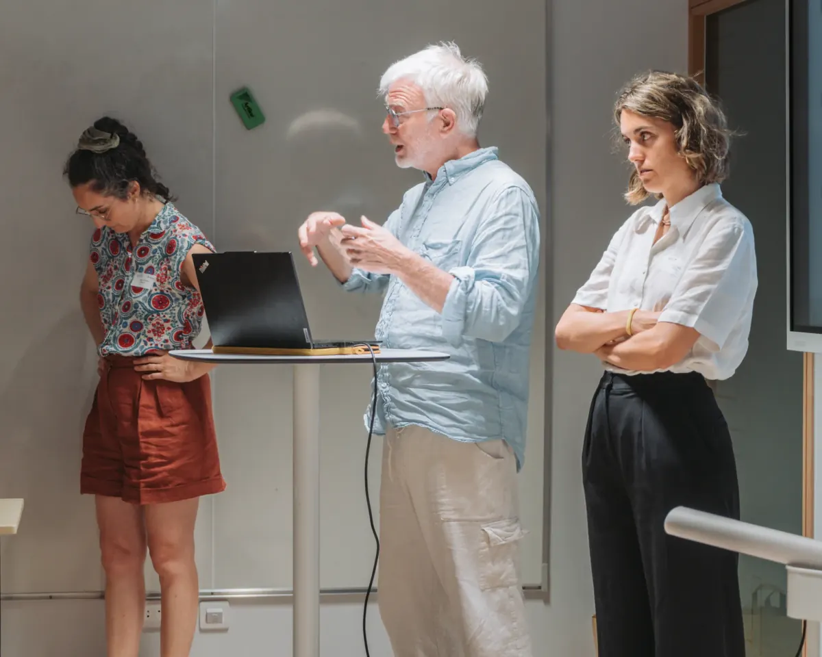 Atelier de séminaire d'entreprise dans une salle à fenêtres, intervenants debout devant les participants en lumière du jour