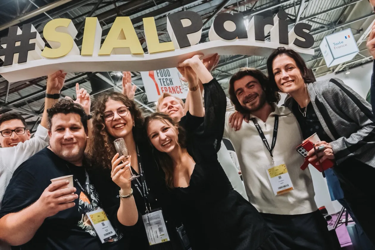 Équipe exposante joyeuse sous l'enseigne du salon SIAL Paris