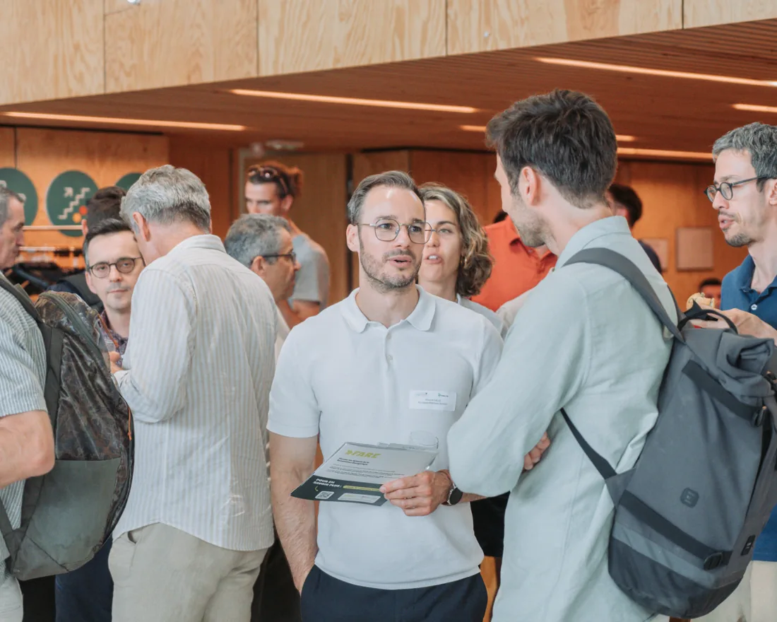 Trois participants en conversation, un dépliant à la main, au moment de la pause d'une journée professionnelle