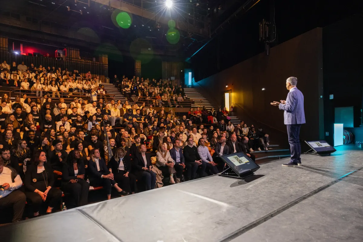 Intervenant sur scène face à un amphithéâtre complet lors d'une conférence d'entreprise